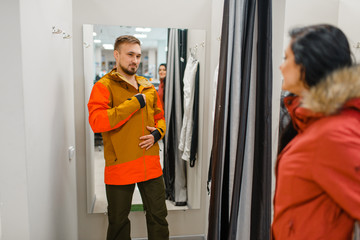 Couple trying on jackets for ski or snowboarding