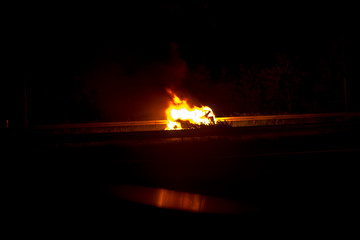Burning car after an accident or defect on the highway