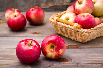 Ripe red apples and basket with apples on a wooden table
