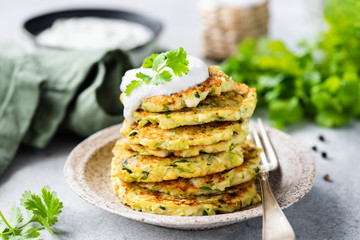 Vegetable zucchini fritters in stack topped with sour cream. Healthy vegetarian food - obrazy, fototapety, plakaty