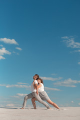 Fototapeta na wymiar Romantic couple dancing in sand desert at blue sky background