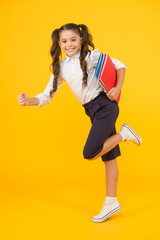 Reader rushing for books. Happy little girl holding books with colorful covers on yellow...