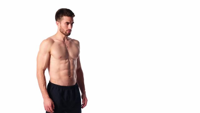 A young sports man with a beard, looking in frame and smiling. The naked torso and muscular muscles of men. Handsome guy looking at camera on a white background
