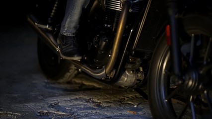 Close-up of foot men in boots on a motorcycle.