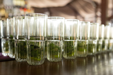 A lot of cocktails at the bar at the wedding party. Glasses with mojito with a slice of lemon and mint close-up