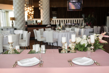 The wedding table setting for the newlyweds is decorated with fresh flowers of carnation, rose, anthurium and eucalyptus leaves. Silver candlesticks, white candles. Wedding floristry. Closeup details