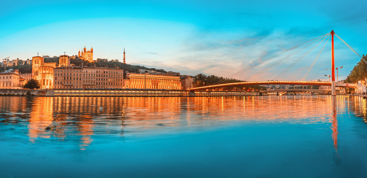 Lyon night cityscape with illuminated Courthouse and red pedestrian bridge over Saone river. Panoramic blue hour landscape