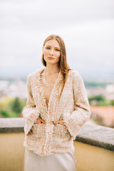 Outdoor fashion portrait of young woman wearing stylish peach colour jacket and silk skirt