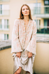 Outdoor fashion portrait of young woman wearing stylish peach colour jacket and silk skirt