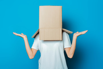 Young woman with a cardboard box on her head on a blue background