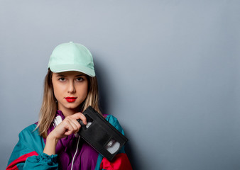 Style woman in 90s clothes style with VHS video cassette