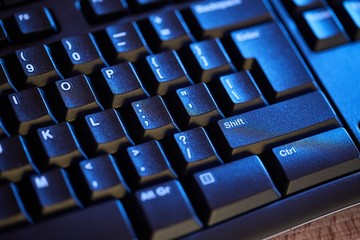 Detail of a black keyboard in blue light