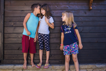 Kids gossiping. Boy whispering something to one girl, other girl eavesdropping