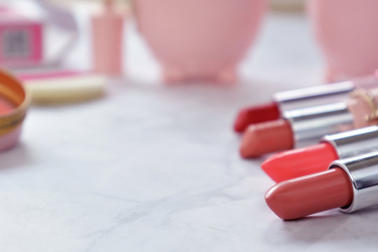 Red And Pink Female Lipsticks On Marbel Desk With Other Pink Cute Beauty Products In Background And Copy Space To The Left