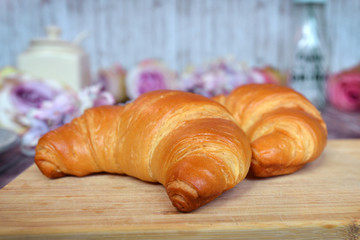 Delicious looking traditional French croissant on wooden plate