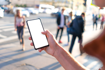 in the hands of a guy is a frameless phone. on a busy city street white screen mockup