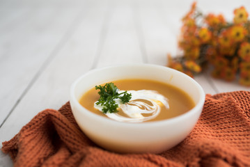 Pumpkin soup with sour cream in white small bowl 