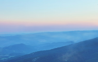 Mountain range with visible silhouettes through the evening fog.