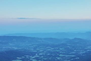 Mountain range with visible silhouettes through the evening fog.