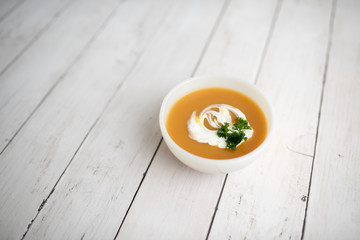 Pumpkin soup with sour cream in white small bowl 