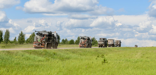 A convoy of oil exploration vehicles moving along the road.