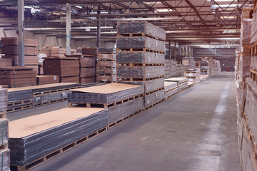 Production line of the wooden floor factory. Warehouse of boards in the production. Pile of cut wood in factory storage warehouse.Lumber in warehouse.