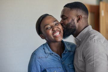 Obraz premium Loving African American husband kissing his wife on the cheek