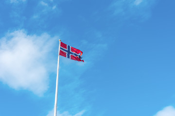 Flag of Norway on a background of blue cloudy sky