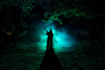 Death with a scythe in the dark misty forest. Woman horror ghost holding reaper in forest