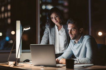 Businesspeople working together on a laptop late in the evening