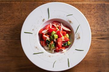 Healthy vegetable salad of fresh tomatoes, cucumbers, bell pepper, onions and herbs. Diet menu. View from above, top studio shot