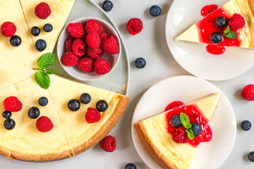 sweet cake or cheesecake with two slices of cake with fresh raspberries, blueberries, jam and mint