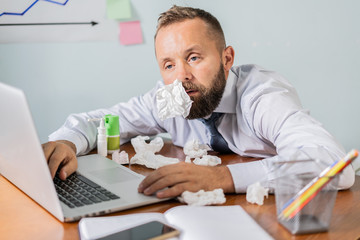 Man with flu working in the office. Bussinessman with hight temperature working in office, man caught cold, seasonal flu. Risk to take infection, boost immune system, seasonal allergy