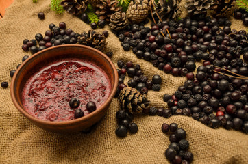 Jam of black Rowan, cones and branches of the Christmas tree on the background of burlap. Preparations for the winter. Gift of nature.