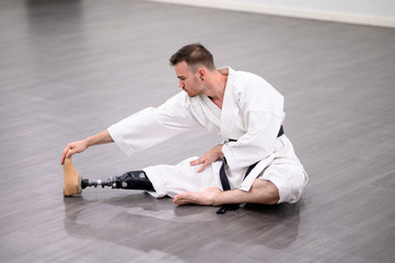 Karate man with prosthetic leg performing gymnastic stretching