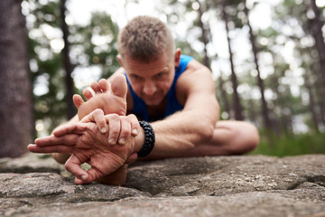 Man doing the head to knee yoga pose outdoors