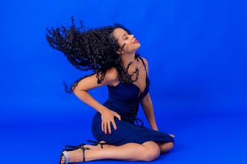 Curly hair girl wearing blue dress studio shot