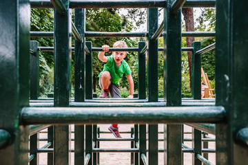 Obraz premium Boy playing in a maze of wooden bars in a park.