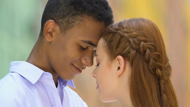 Beautiful multiethnic couple of lovers touching foreheads, enjoying each other