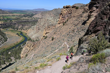 Hikers on Misery Ridge Trail in Smith Rock State Park near Terrebonne, Oregon on a cloudless summer day.