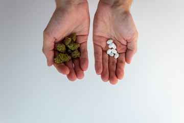 Traditional vs natural medicine. Hands holding pills and marijuana