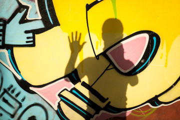 Silhouette waving over a yellow graffiti