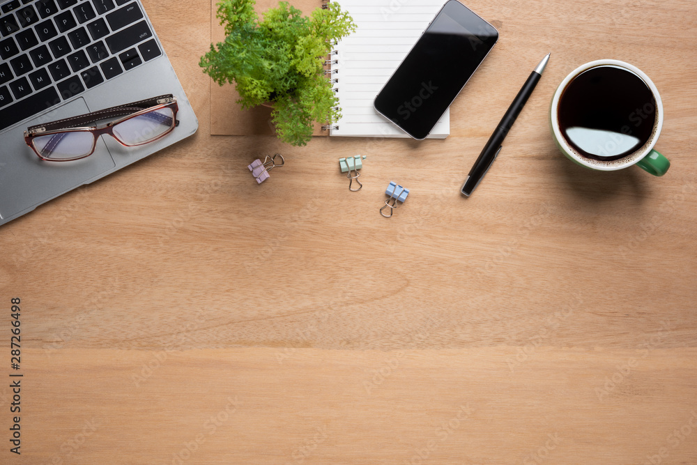 Poster wooden office desk table with smartphone with blank mock up screen, laptop computer, cup of black co
