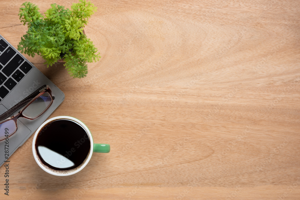 Poster wooden office desk table with laptop computer, cup of black coffee and supplies. top view with copy 