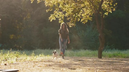 Attractive young woman playing with jack russel terrier in park during beautiful sunset, super slow motion