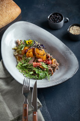 Salad with duck strawberries and mango on a dark background, low key. Food photo concept. Restaurant food, food advertising for social networks.