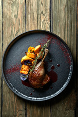 Roasted duck leg with confit pumpkin, closeup. Horizontal top view, top shot. Copy space, wooden...
