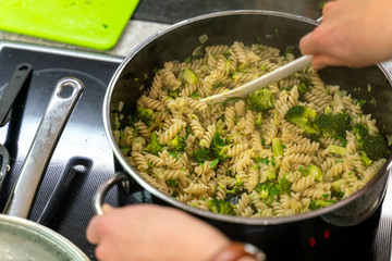 Pasta and broccoli are fried in a pan