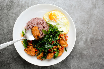 Crispy chicken cooked with green basil, served with steamed rice and fried egg, hot and spicy dish with basil leaves.