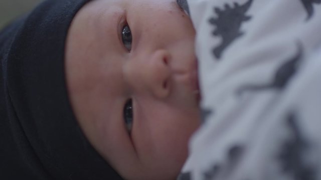 Newborn baby swaddled smiling in slow motion